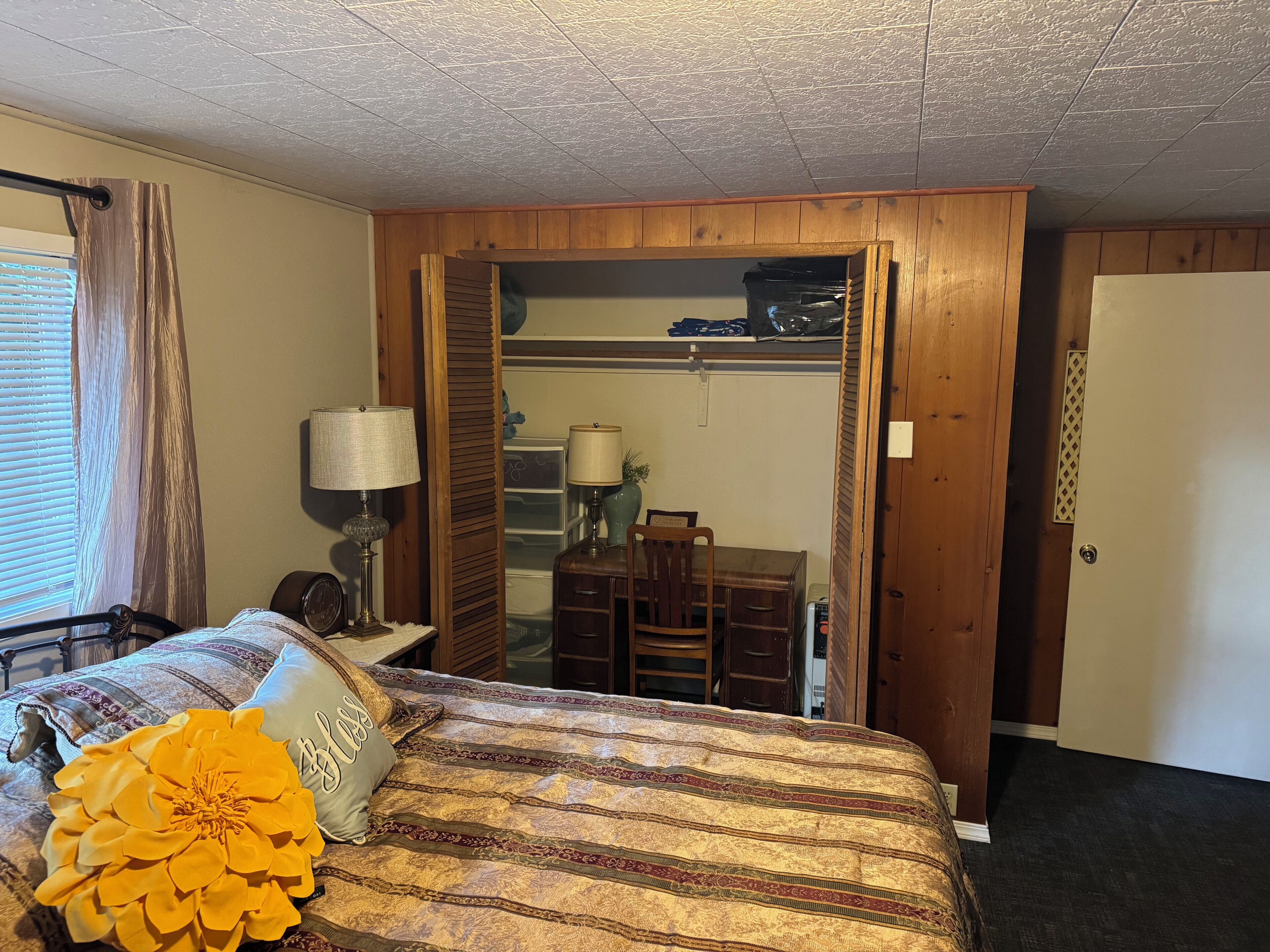 Een hotelkamer met een bed, een bureau, een stoel, een lamp en een kledingkast.