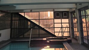 Ein moderner, überdachter Pool mit Glaswänden und Blick auf ein Gebäude.