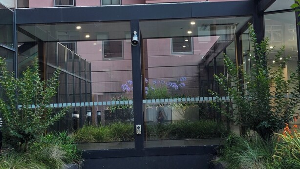 Ein modernes Gebäude mit einer flachdachartigen Terrasse, Glasgeländern und Pflanzkübeln.