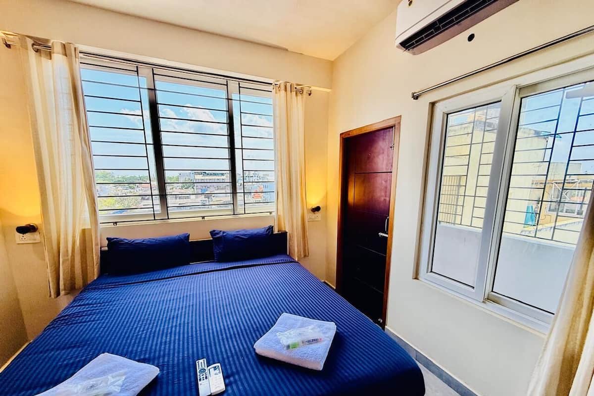 A hotel room with a large bed, two pillows, a remote control, and a towel on the bed.