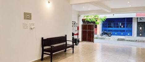 A spacious room with a wooden bench, ceiling fan, and a view of the street outside.