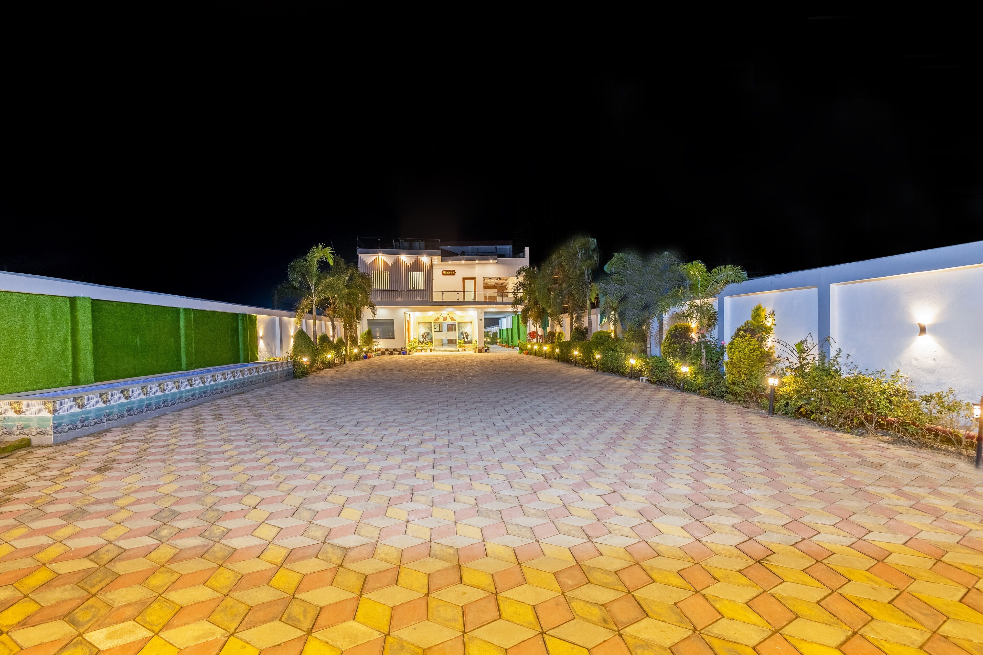 A paved walkway leading to a building with a green wall and a tiled entrance.