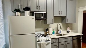 Eine kompakte Küche mit Kühlschrank, Mikrowelle, Herd, Spüle und Schränken.