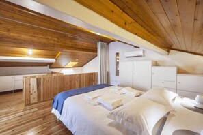 A bedroom with a wooden ceiling, a bed with white linens, a nightstand, and a wardrobe. - Casa Azul - Beach House (Ponta Delgada)