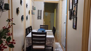 A narrow dining area with a table set for two, chairs, and a decorative plant.