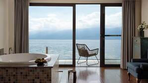 Een badkamer met een groot bad, een stoel en uitzicht op zee.