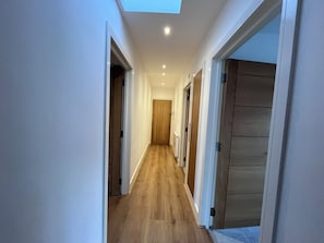 A narrow hallway with wooden flooring, white walls, and a skylight. - Sleek Modern 2BDR Flat in Charming Pinner (Greater London)