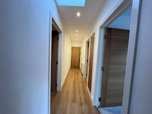 A narrow hallway with wooden flooring, white walls, and a skylight. - Sleek Modern 2BDR Flat in Charming Pinner (Greater London)