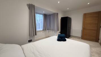 A hotel room with a bed, a wardrobe, and a window with curtains.