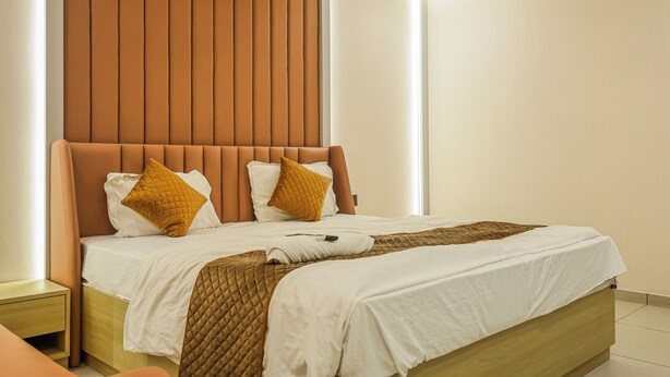 Habitación de hotel moderna con una cama grande, cabecera de madera y una paleta de colores neutros.
