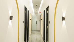 Un pasillo moderno de hotel con un camino recto, puertas a ambos lados y una puerta de cristal al final.