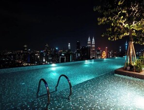 An infinity pool with a city skyline view at night. - Expressionz Suites by Mana Mana (Kuala Lumpur)