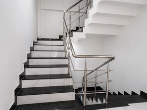 Un escalier avec des marches en marbre noir et blanc, des rampes en métal et un mur blanc en arrière-plan.