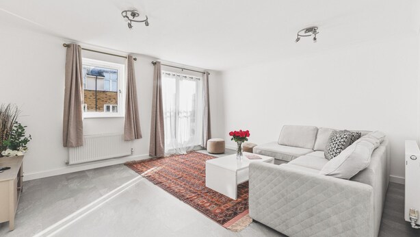 Ein modernes Wohnzimmer mit einer Couch, einem Couchtisch und einem gemusterten Teppich.