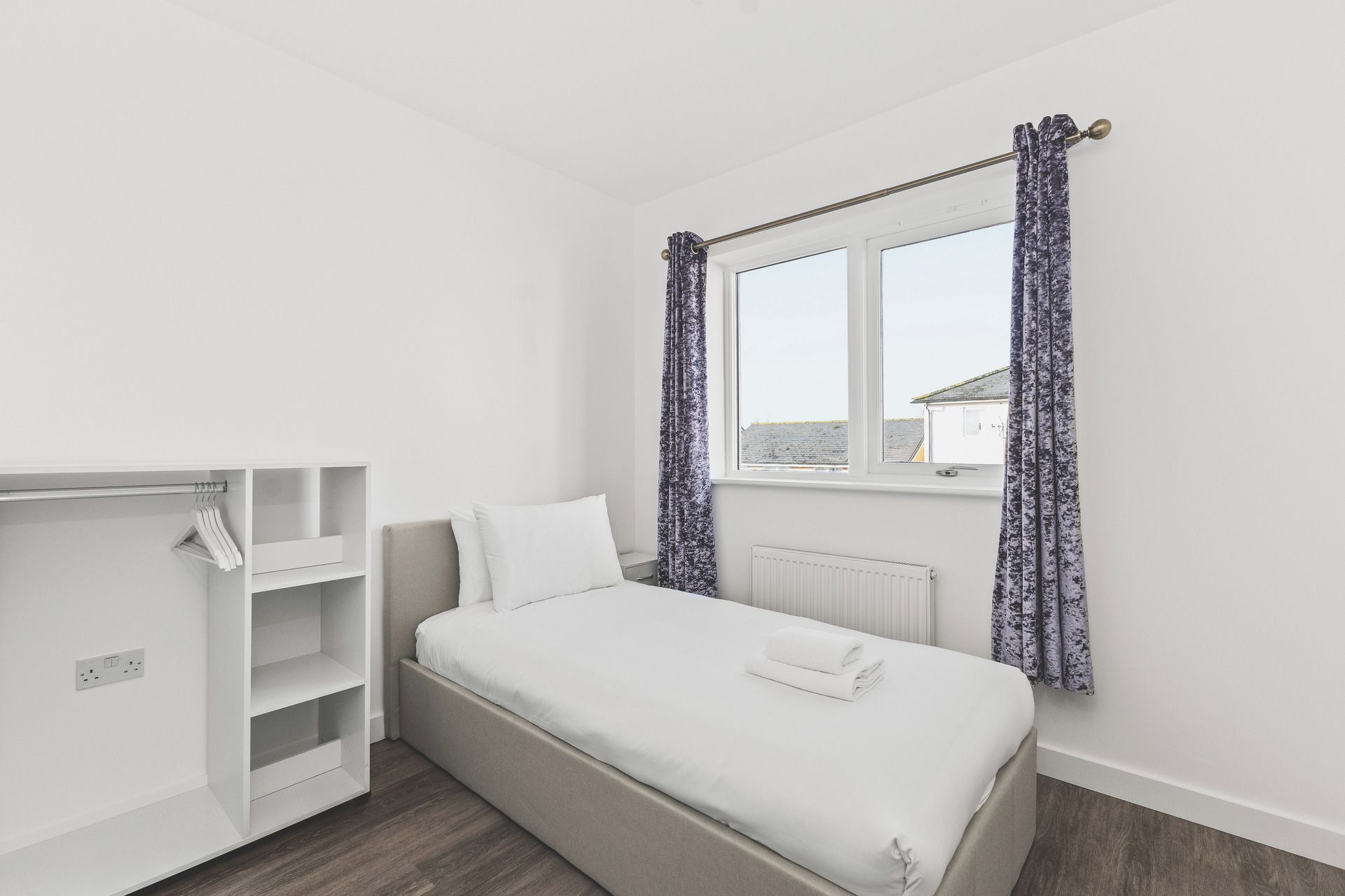 Ein Schlafzimmer mit einem Bett, einem Kleiderschrank und einem Fenster mit Vorhängen.
