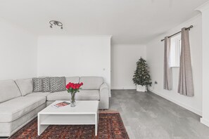 A modern living room with a grey sofa, a white coffee table, a patterned rug, and a Christmas tree. - Beautiful 4BDR Townhouse with Free Parking (Hayes)