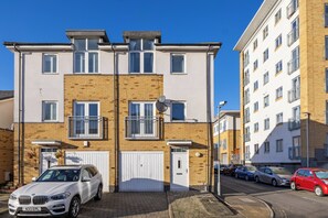A multi-story residential building with a brick facade, white doors, and balconies. - Beautiful 4BDR Townhouse with Free Parking (Hayes)