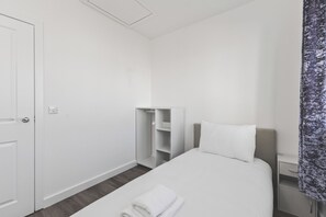 A hotel room with a bed, a wardrobe, and a nightstand. - Beautiful 4BDR Townhouse with Free Parking (Hayes)