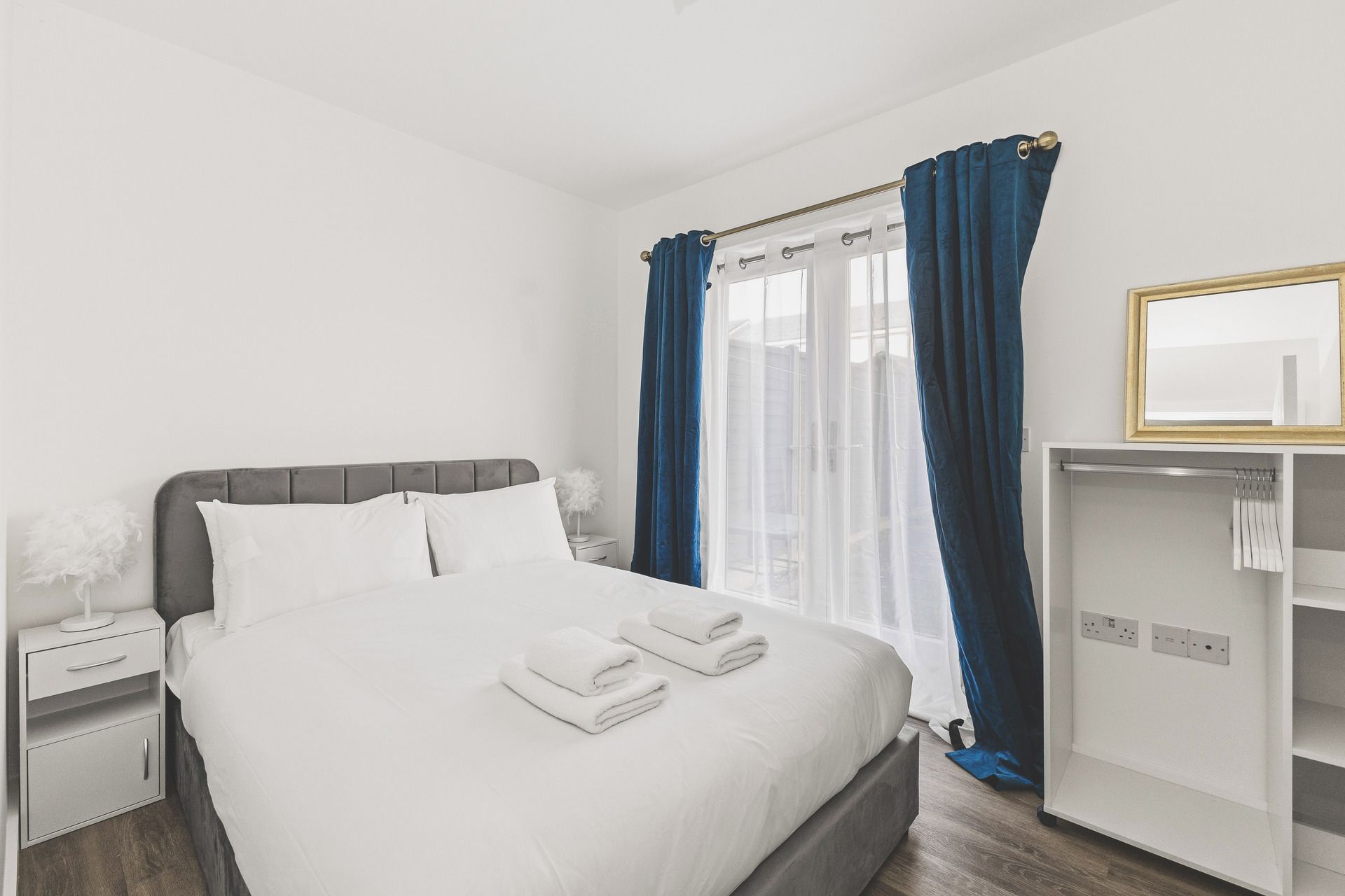 A hotel room with a bed, a nightstand, a wardrobe, and a window with curtains.