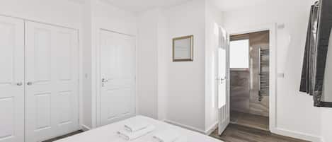 Habitación de hotel con cama, armario, espejo y baño con perchero.