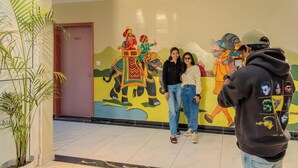 A lobby with a mural of an elephant and people, a potted plant, and a tiled floor.