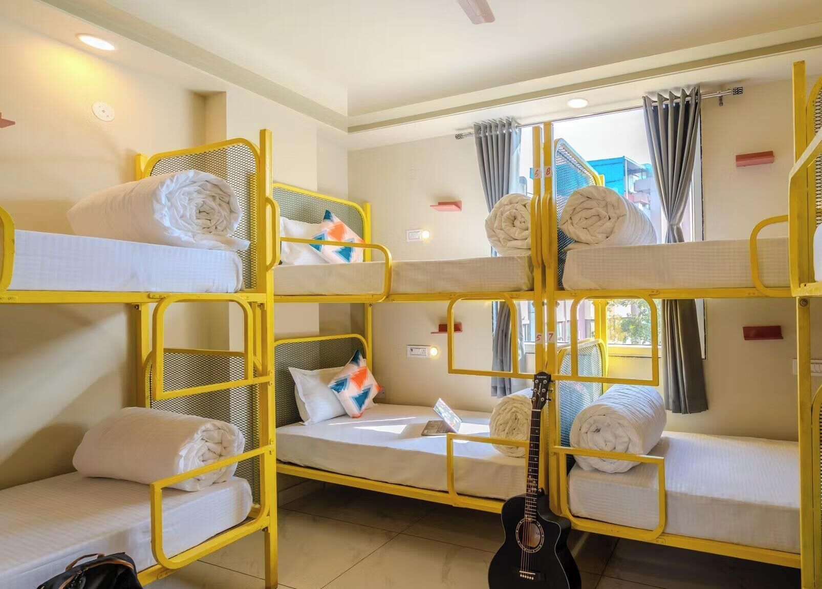 A bunk bed room with a guitar, towels, and a window with curtains.