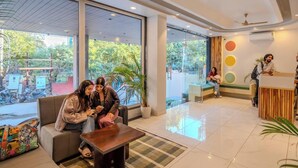 A modern hotel lobby with seating areas, a reception desk, and large windows offering a view of the outdoors.