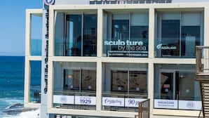 A multi-story building with signage for 'Bondi Icebergs' and 'sculpture by the sea'. - Bondi Beach Breeze - Walk to Beach and Shops (Bondi Beach)