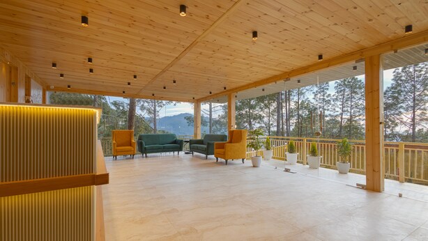 A covered outdoor area with wooden flooring, green and yellow chairs, and potted plants. - Sterling Valley of Pine Lansdowne (Lansdowne)