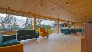 A spacious indoor area with wooden flooring and ceiling, featuring a green sofa, a yellow armchair, and a green couch. - Sterling Valley of Pine Lansdowne (Lansdowne)