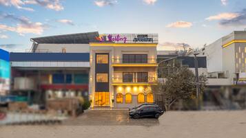 Un edificio moderno con un letrero que dice "Saru Ayodhya" y "Starling". Tiene techo plano, una escalera y un coche estacionado en frente.