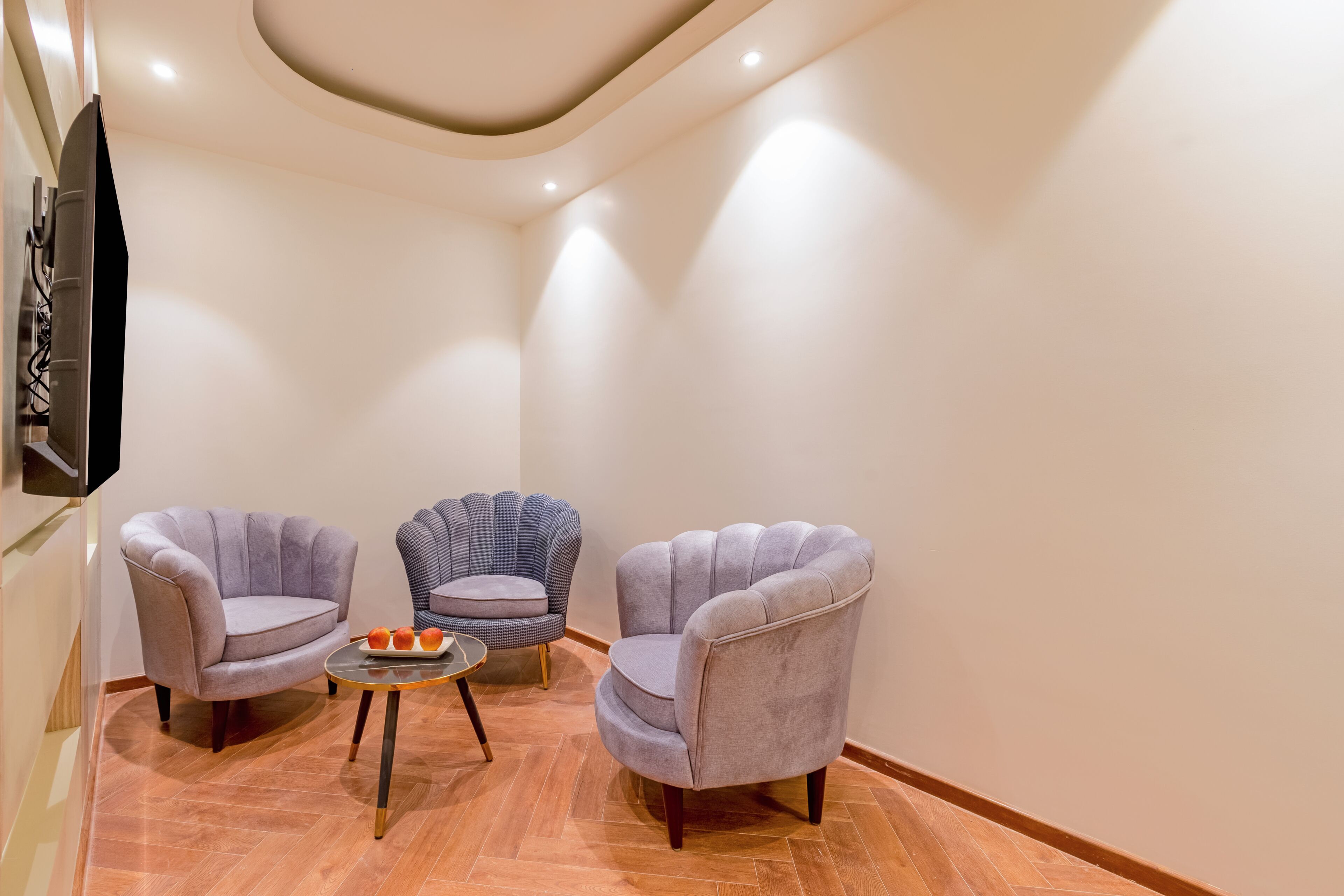 A modern room with two grey armchairs, a small round table with a fruit tray, and a unique blue armchair.