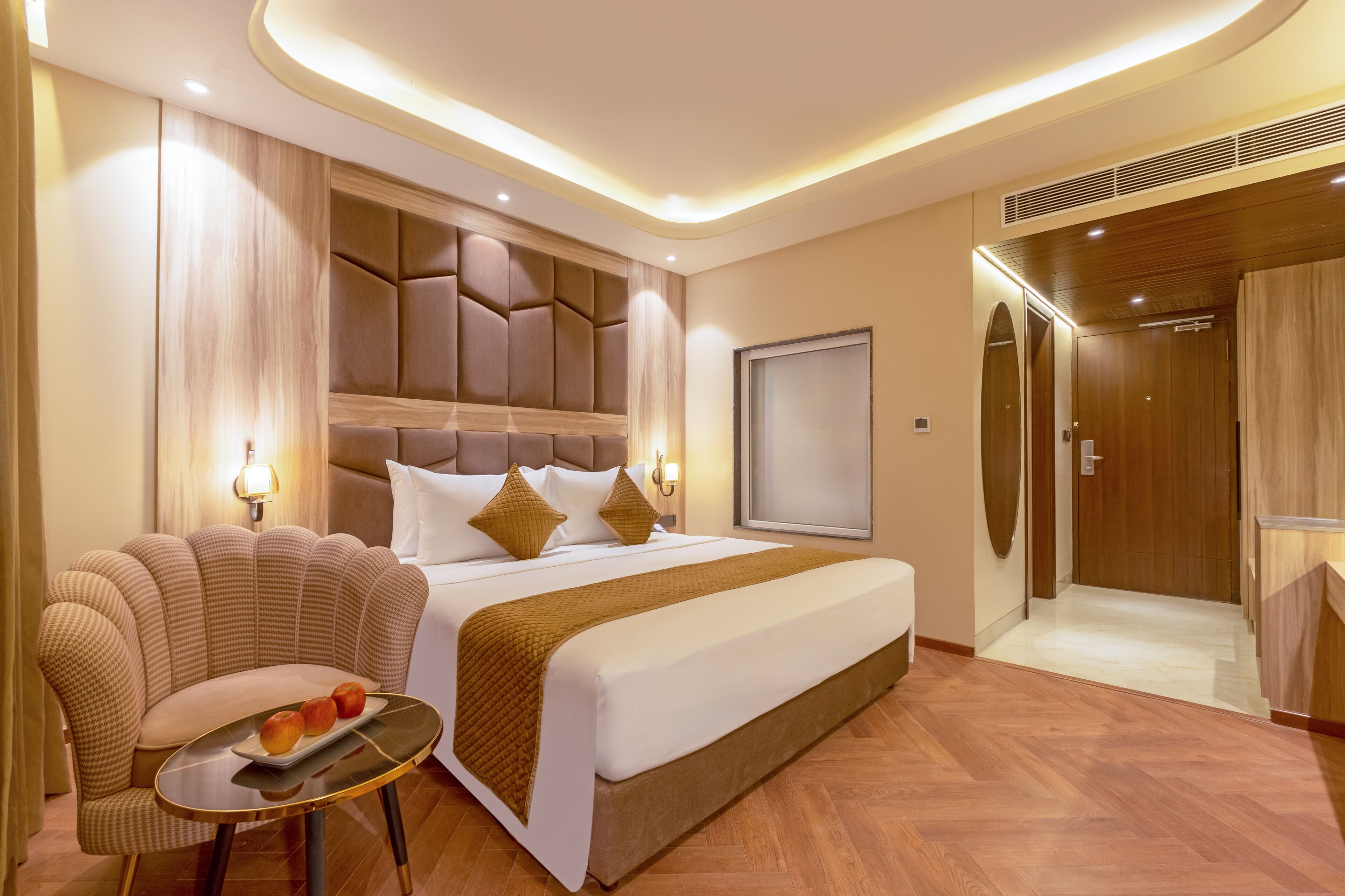 Una habitación de hotel moderna con una cama grande, una zona de estar con una mesa y un vestidor separado.