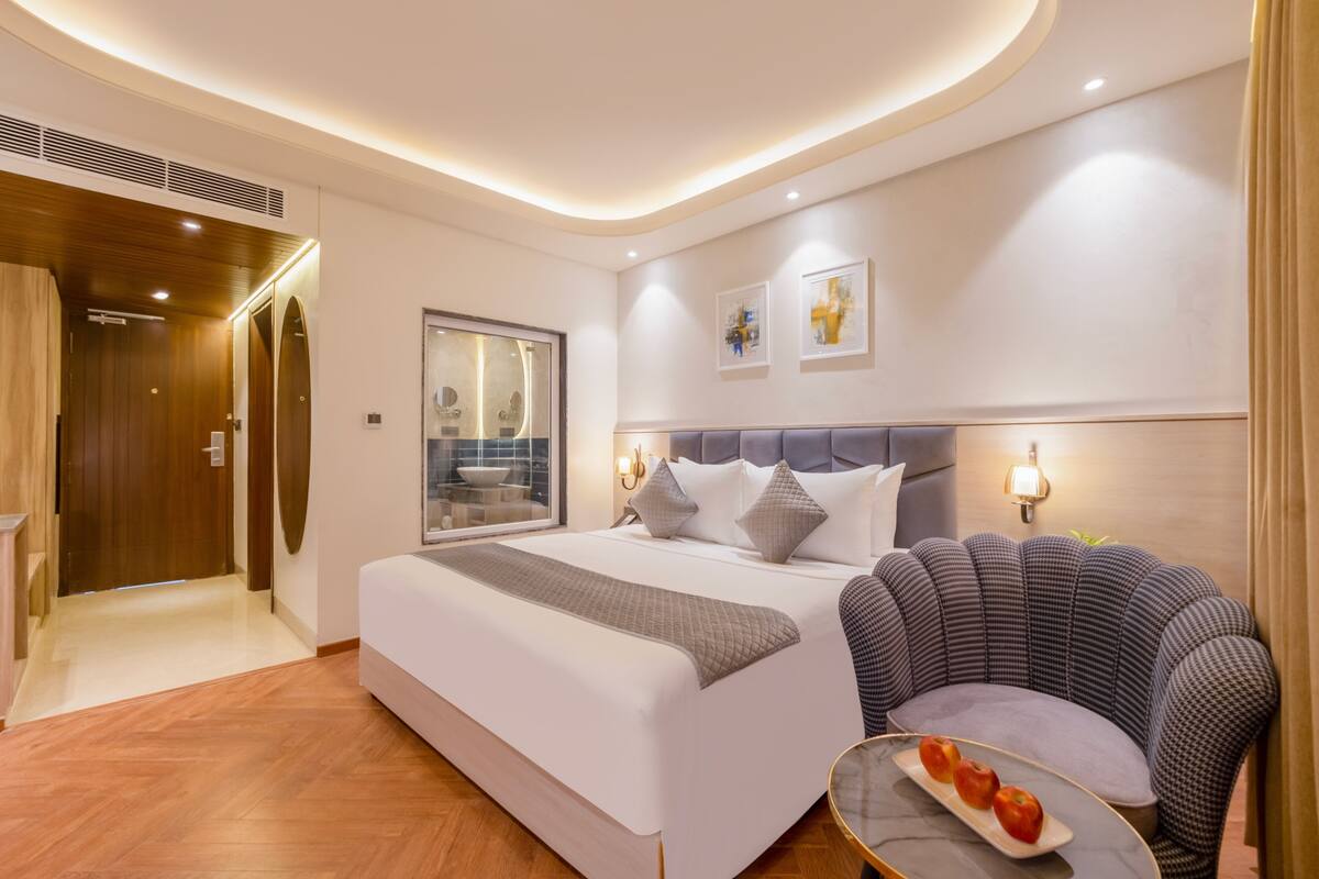 Una habitación de hotel moderna con una cama grande, un área de descanso y vistas a la ciudad.