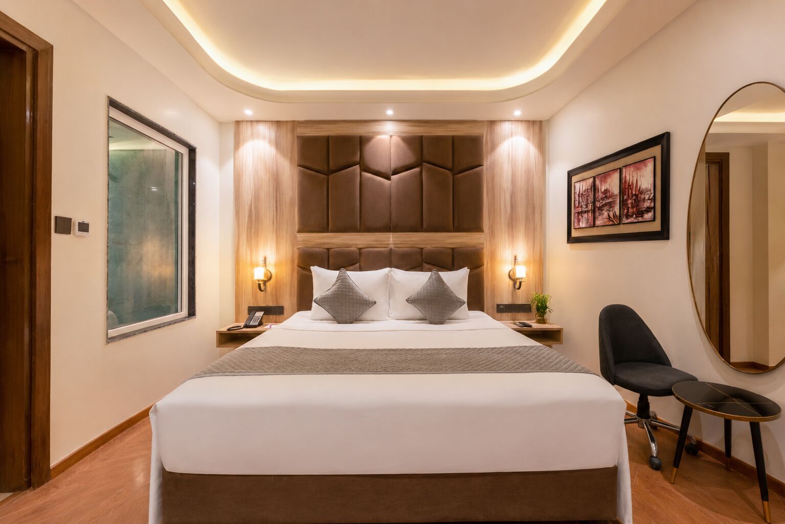 A modern hotel room with a large bed, a desk, and a chair.