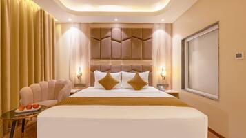 A hotel room with a large bed, a seating area with a table, and a view of the outside.