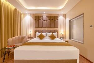 A hotel room with a large bed, a seating area with a table, and a view of the outside.