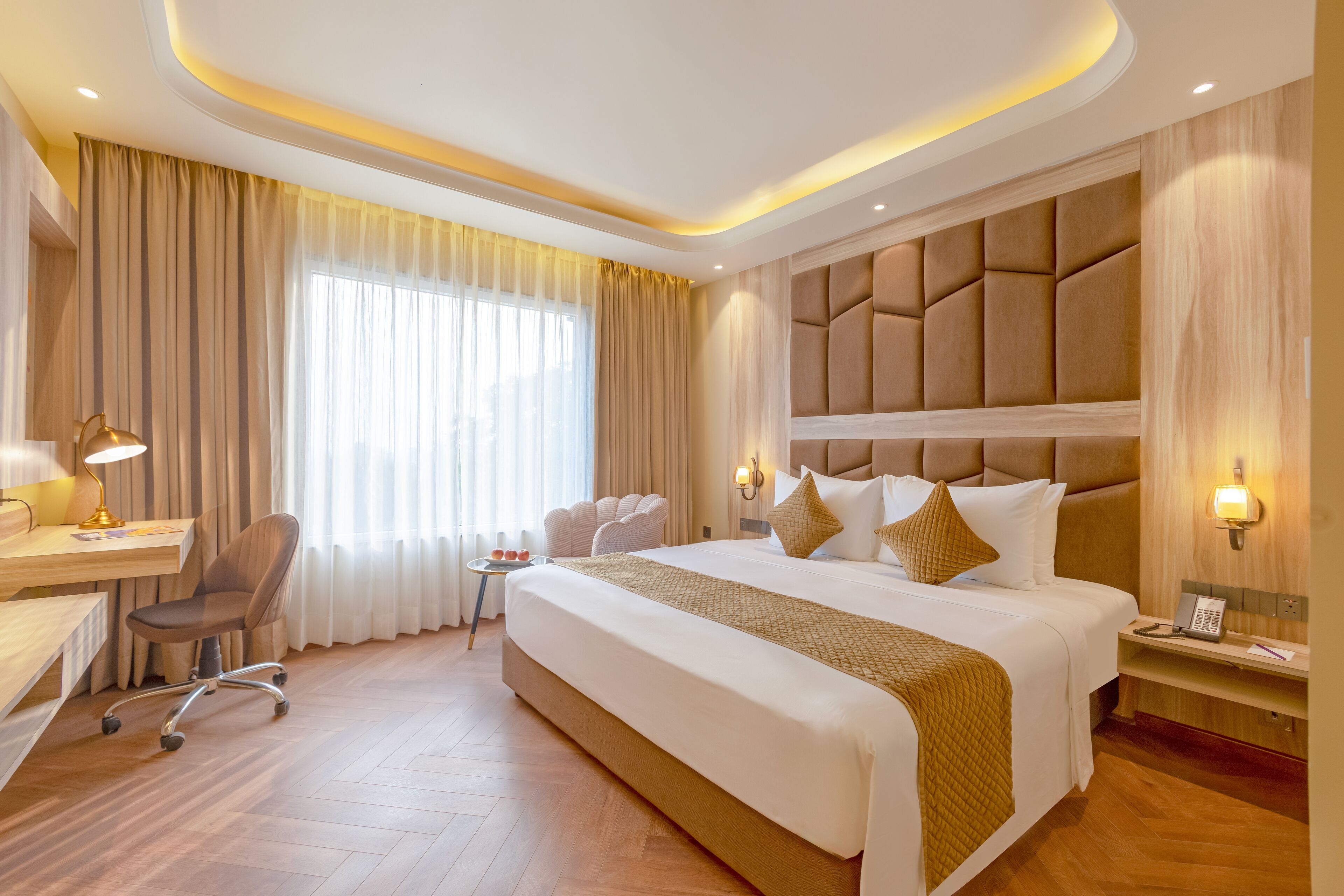 A hotel room with a large bed, a desk, a chair, and a sofa.