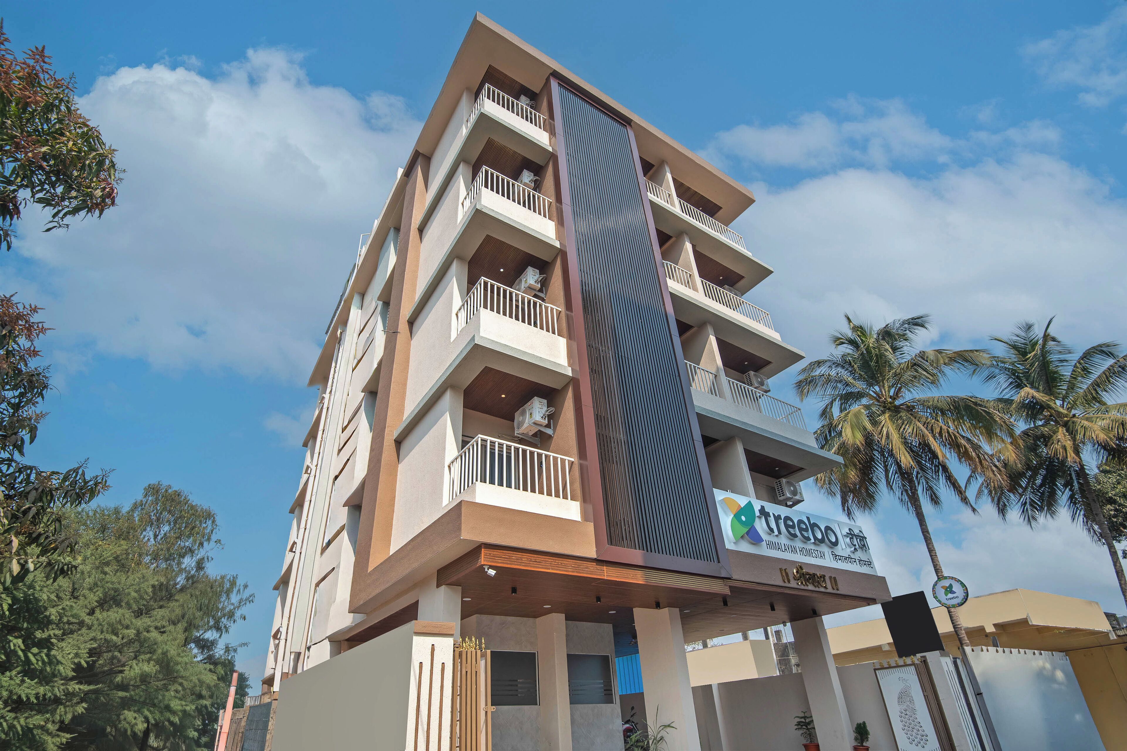 Un edificio de varios pisos con balcones, una característica vertical destacada y un letrero que dice 'treebo'.