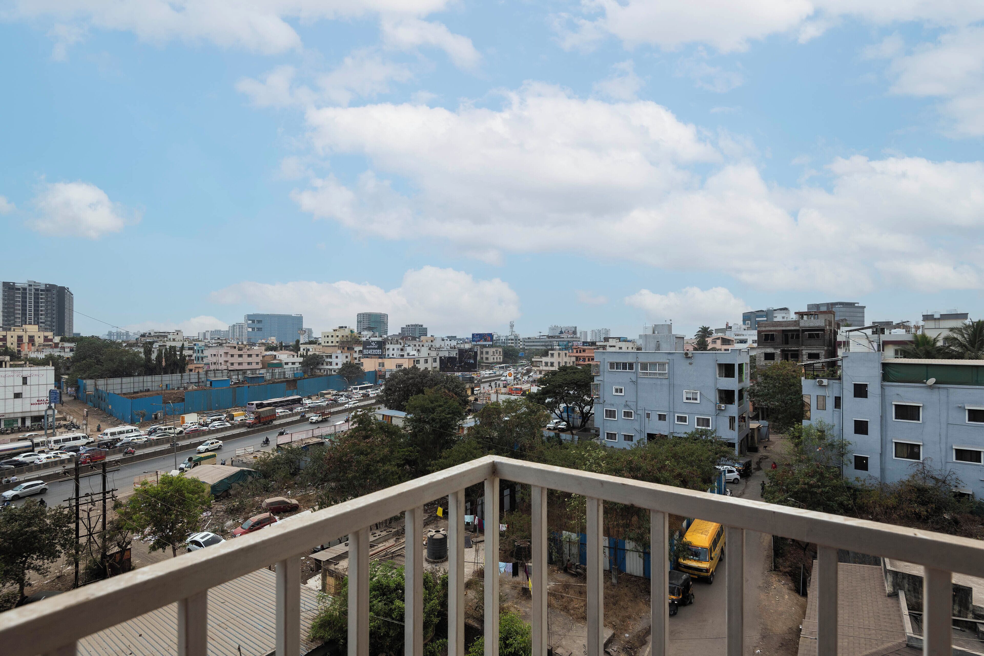 Un paisaje urbano con diversos edificios, una calle concurrida y cielo despejado.