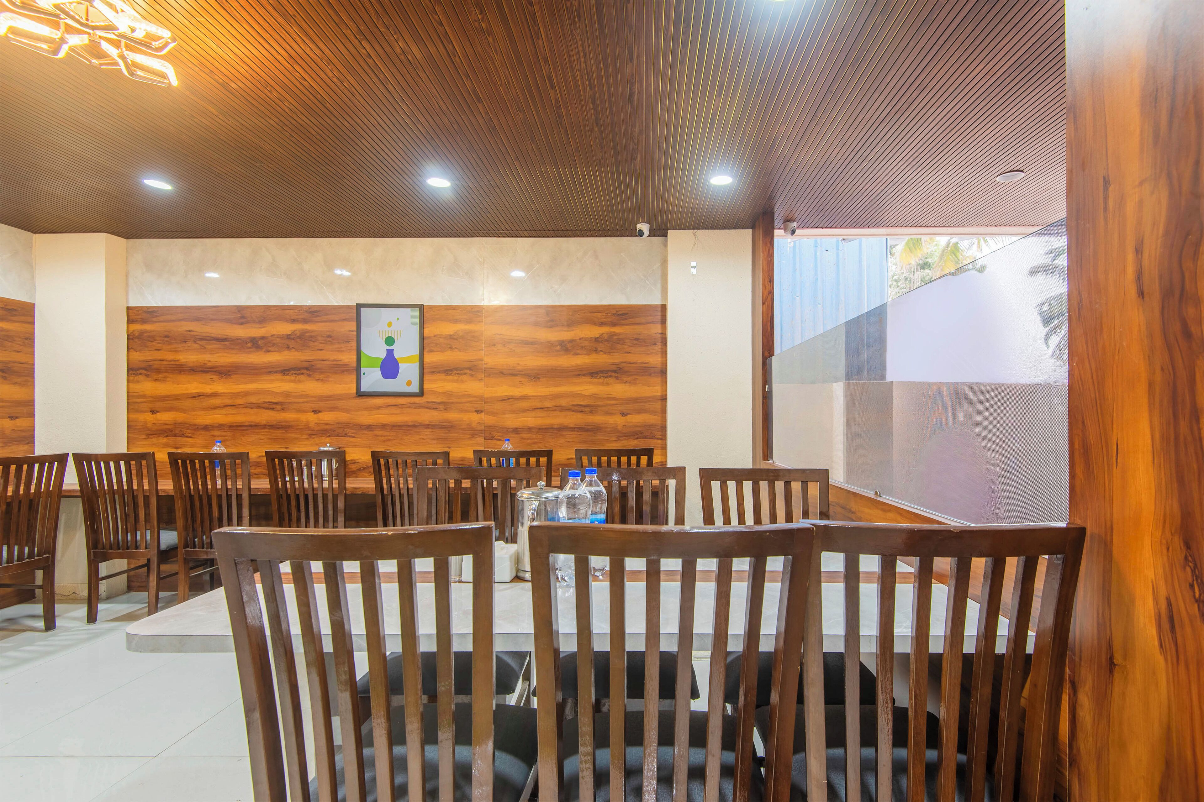 Un restaurant avec des chaises et des tables en bois, un plafond en bois et un mur orné d’un tableau.