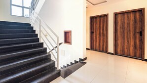 A staircase with a handrail leading to a landing, a wooden door, and a window. - Treebo Himalayan Homestay (Pune)