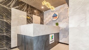 A reception desk with a marble and grey finish, a logo for 'treebo', and a sign with 'HHS' and a mountain icon. - Treebo Himalayan Homestay (Pune)