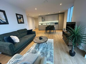 Un salon moderne comprenant un canapé, une table basse et un coin repas avec des chaises.