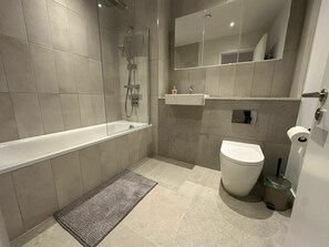 Une salle de bain moderne équipée d’une baignoire, de toilettes et d’une douche.