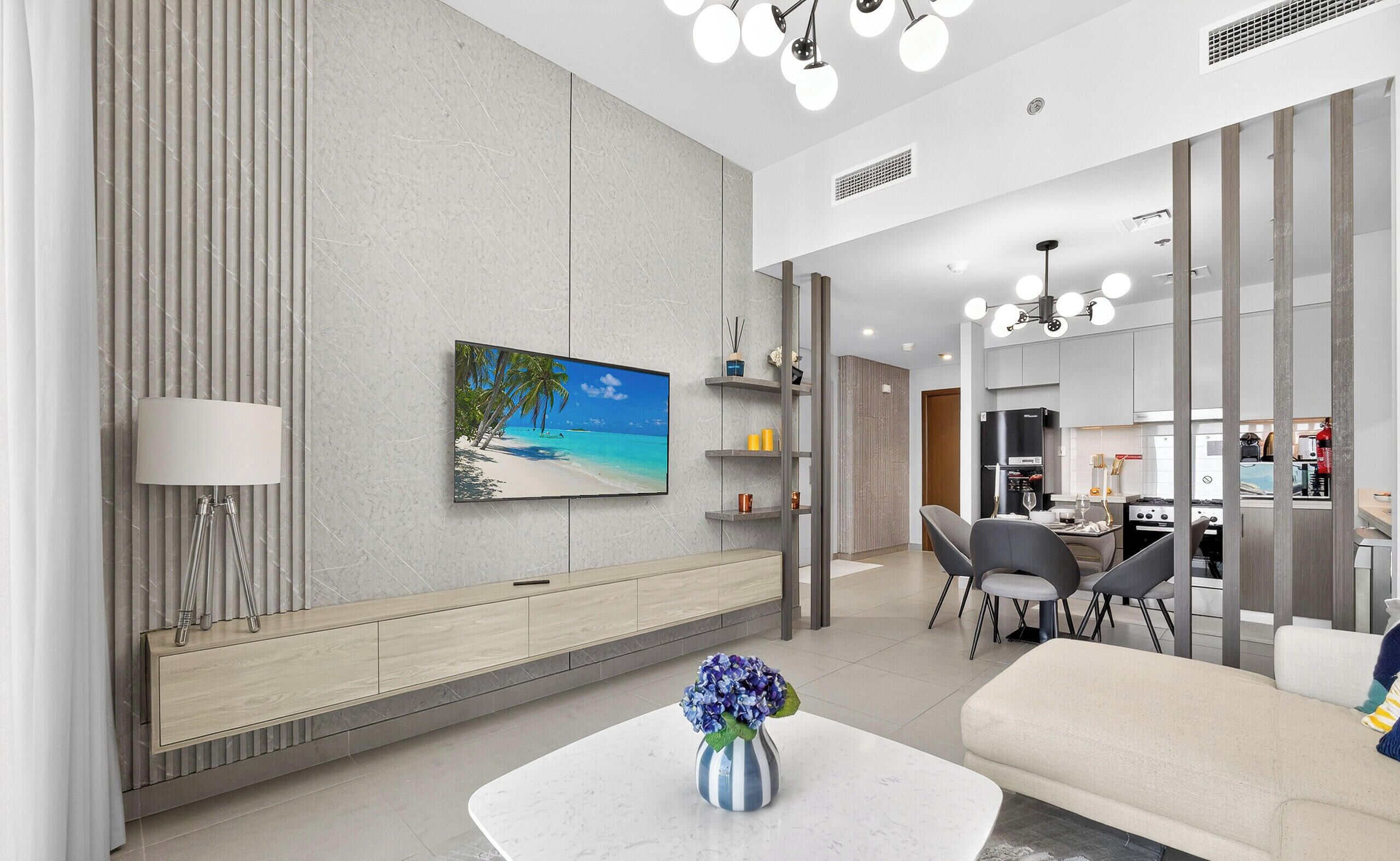 Een moderne woonkamer met een flatscreen televisie, een eethoek en een keuken.