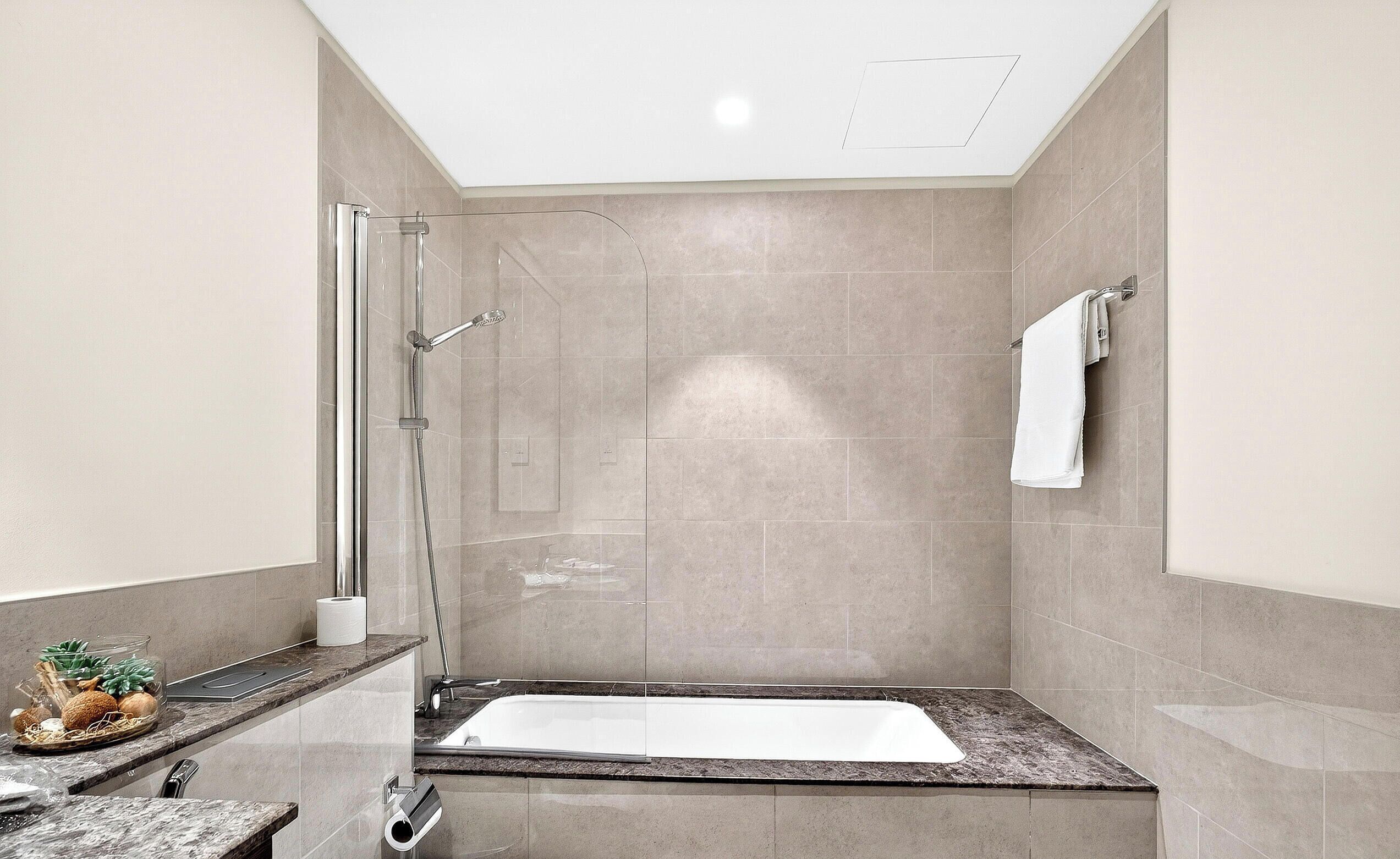 A modern bathroom with a glass-enclosed shower, a freestanding bathtub, and a towel rack.