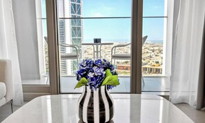 A modern hotel room with a large window, a white table, and a vase with flowers. - WYZ RENT|Modern 1BR Forte Near Burj & Mall (Dubai)