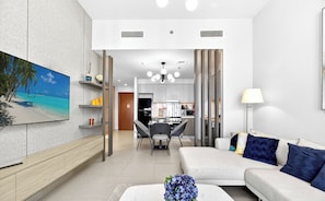 A modern living room with a sofa, a coffee table, a dining area, and a kitchen in the background. - WYZ RENT|Modern 1BR Forte Near Burj & Mall (Dubai)