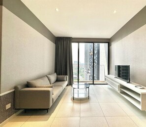 A modern living room with a sofa, a glass coffee table, a TV on a white stand, and a balcony with a city view. - Millerz Square by Mana Mana (Kuala Lumpur)